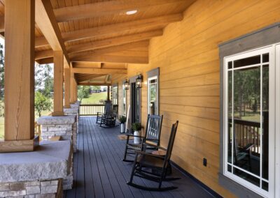 Wooden porch with rocking chairs and rural view.