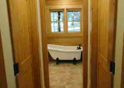 View of wooden hallway leading to bathroom.
