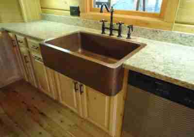 Rustic kitchen sink with wooden cabinets and granite countertop.