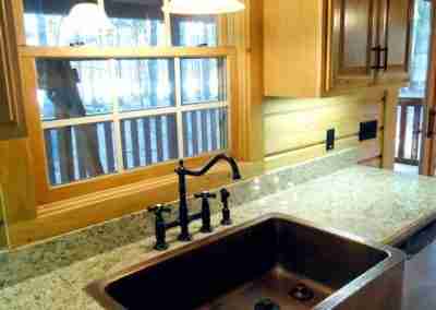 Bronze sink with granite countertop and window view.
