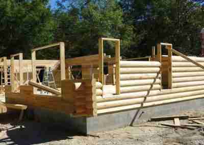 Log cabin construction in a forested area.