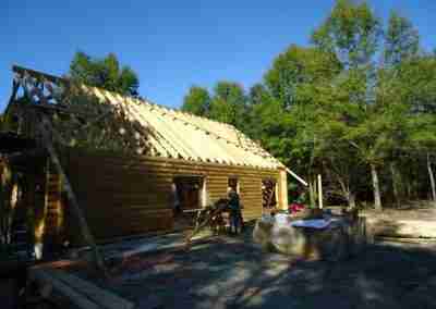 Workers constructing a log cabin outdoors.