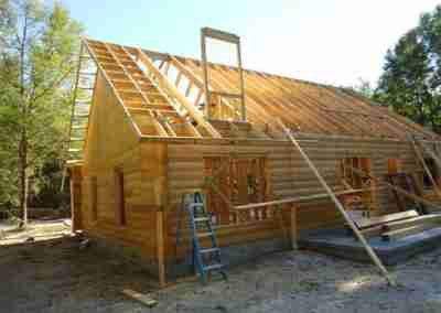 Log cabin under construction with wooden frame.