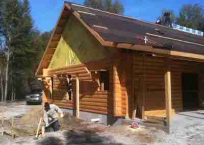 Log cabin construction in progress with workers.