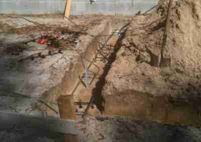 Construction site with foundation and tools visible.