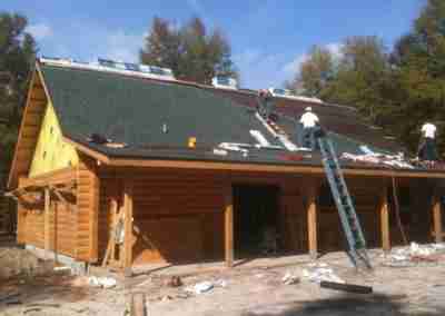 Workers installing a roof on a wooden cabin.
