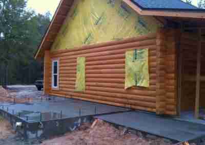 Log cabin under construction with yellow insulation.