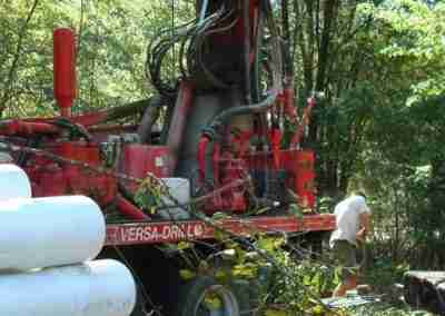 Red drilling machine in a forested area.