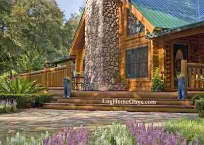 Beautiful log cabin with stone chimney and flowers.