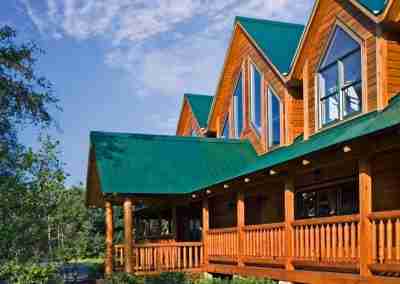 Wooden cabin with green roof and lush garden.
