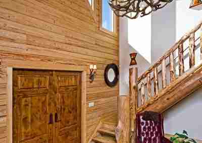 Spacious wooden entryway with staircase and chandelier.