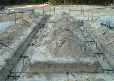 Construction site with foundation and gravel mounds.