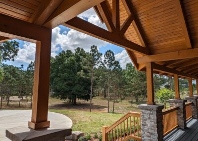 Wooden porch overlooking trees and clear sky.